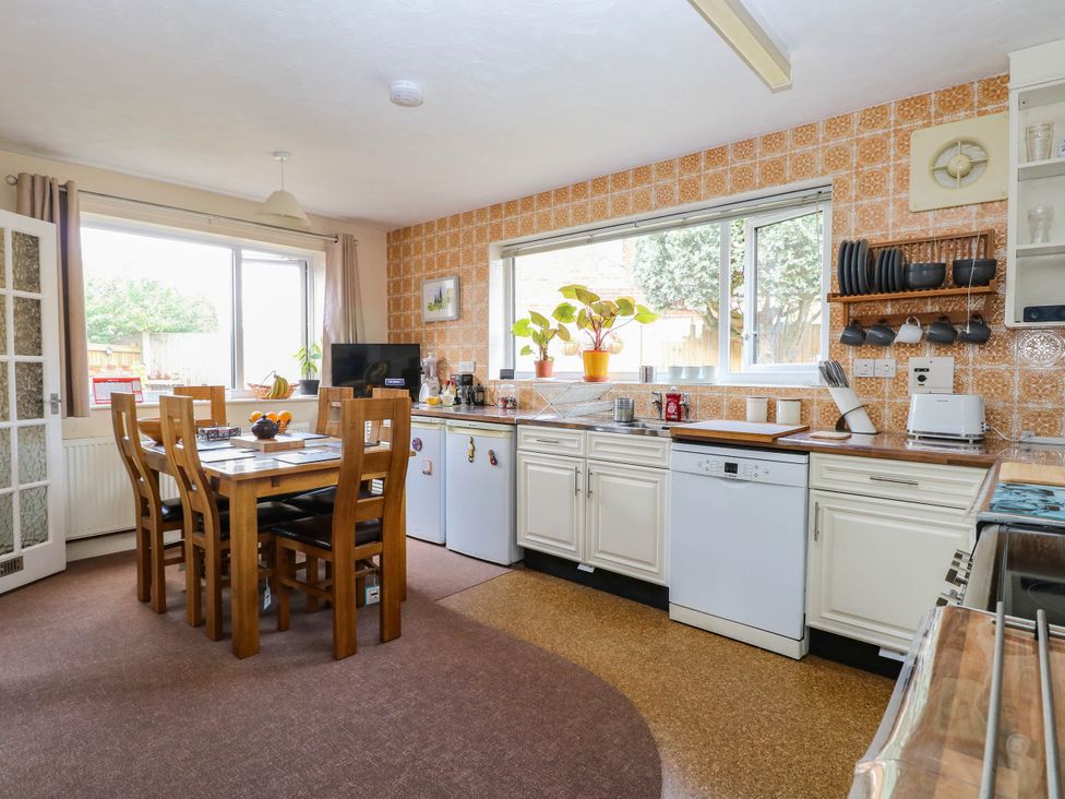A kitchen with dining table and appliances at The Bungalow in Burgh Castle