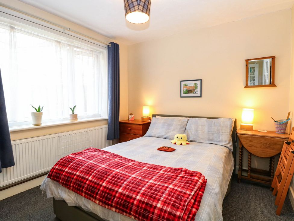 A bedroom with a bed and plants on the window sill at The Bungalow in Burgh Castle
