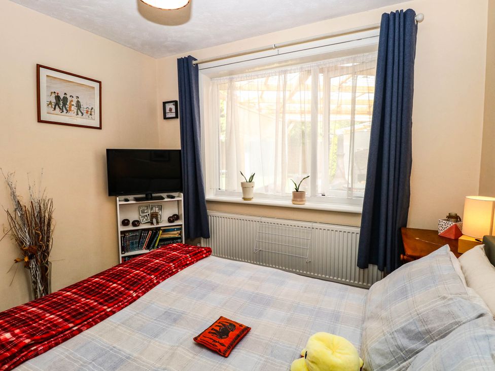 A bedroom with a bed and television at The Bungalow in Burgh Castle
