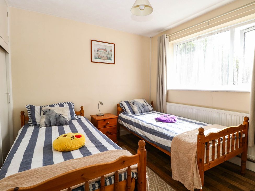 A bedroom with two beds and a nightstand at The Bungalow in Burgh Castle