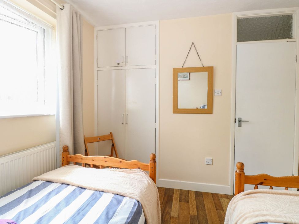 A bedroom with two beds and a wardrobe at The Bungalow in Burgh Castle