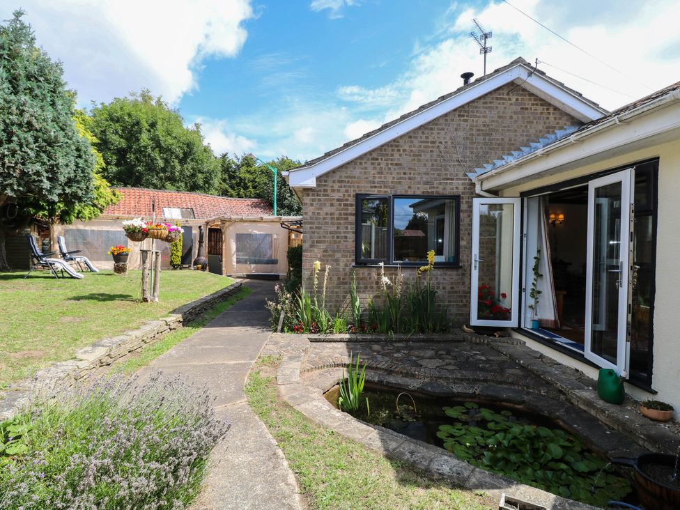 A garden with a house and pond at The Bungalow in Burgh Castle
