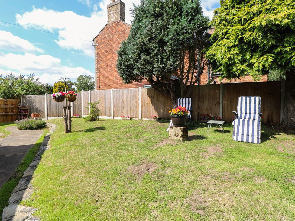 A garden with chairs and flower pots at The Bungalow in Burgh Castle