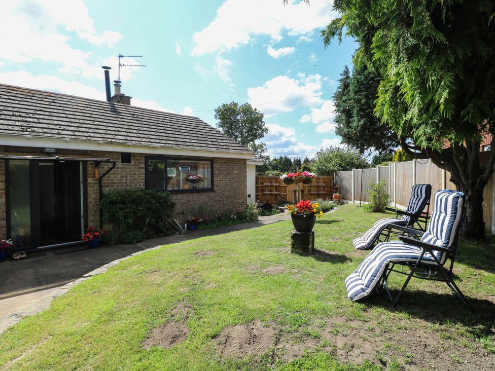 A garden with chairs and flower pots at The Bungalow in Burgh Castle