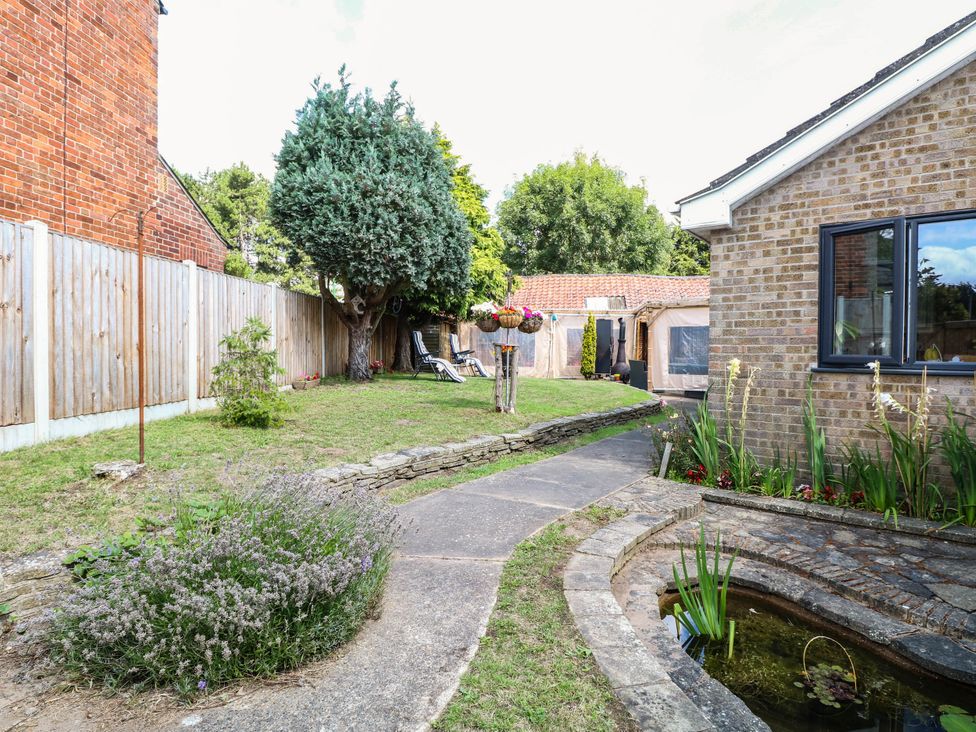 A garden with a pathway, shed, and flower bed at The Bungalow in Burgh Castle