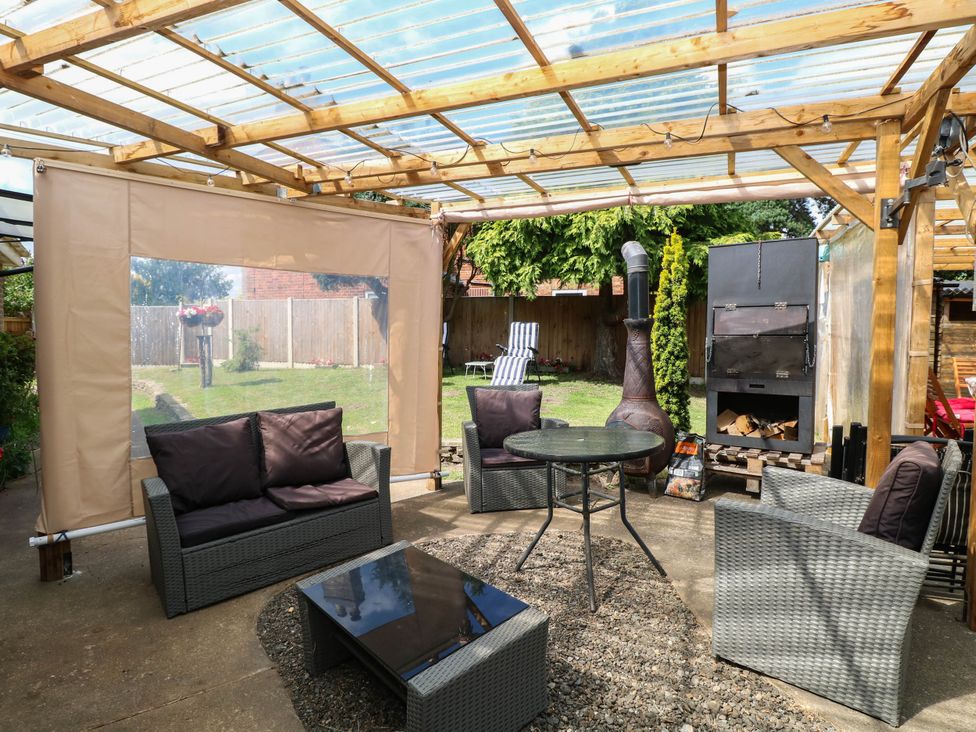 An outdoor living area with seating and a chiminea at The Bungalow in Burgh Castle