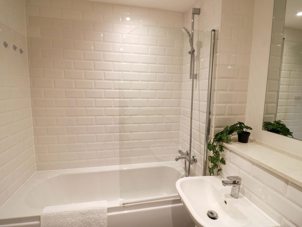 A bathroom with a bathtub, sink, and mirror at Park-View Nook in Birmingham
