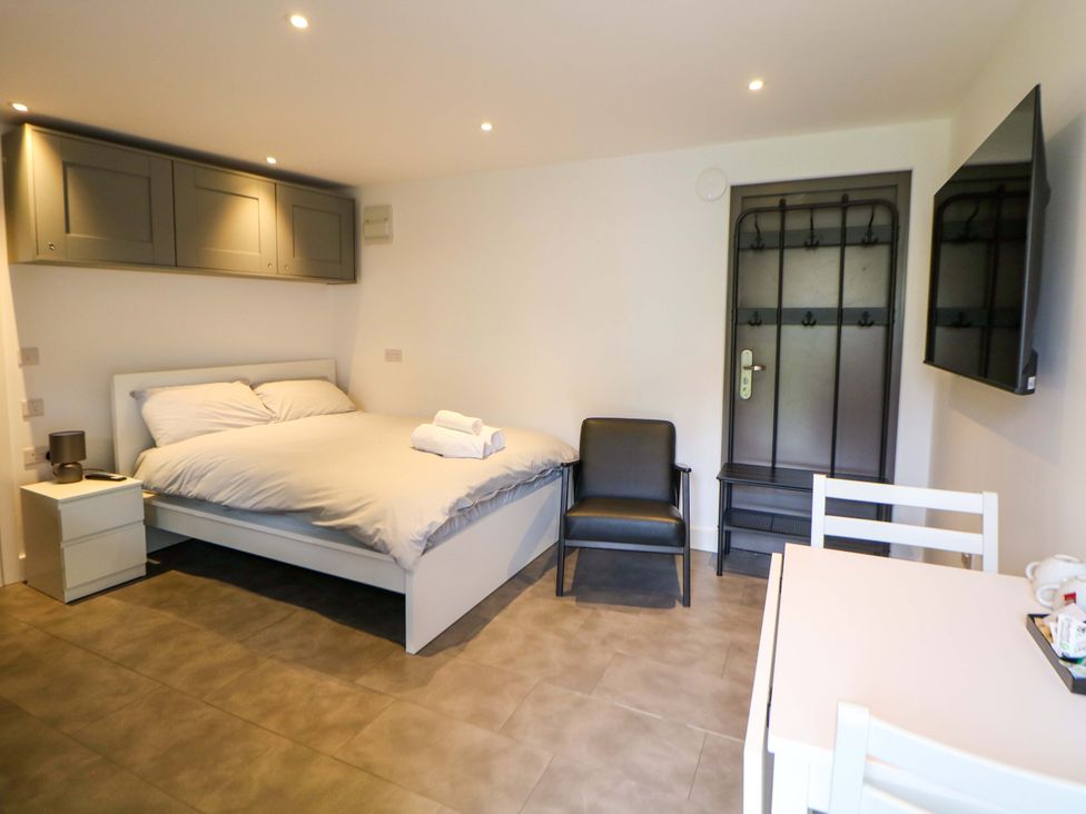 A bedroom with a bed, chair, table and television at Dore Cabin in Sheffield