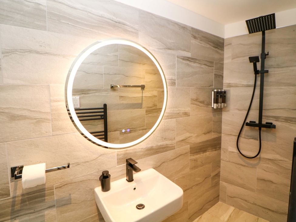 A bathroom with a mirror, sink, and shower at Dore Cabin in Sheffield