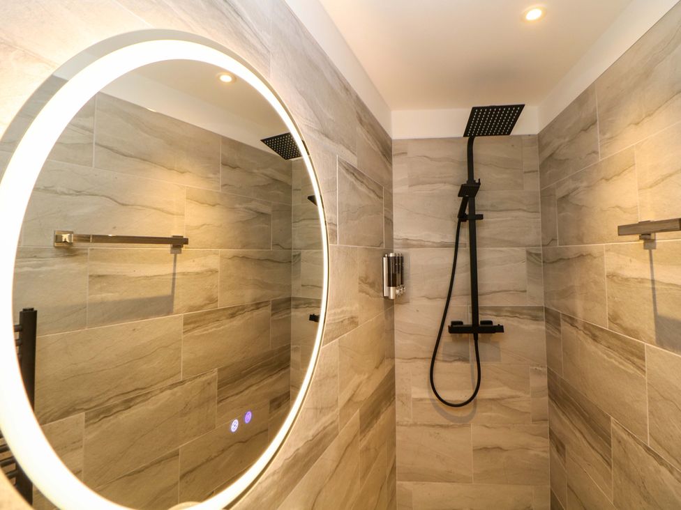 A bathroom with a shower and mirror at Dore Cabin in Sheffield