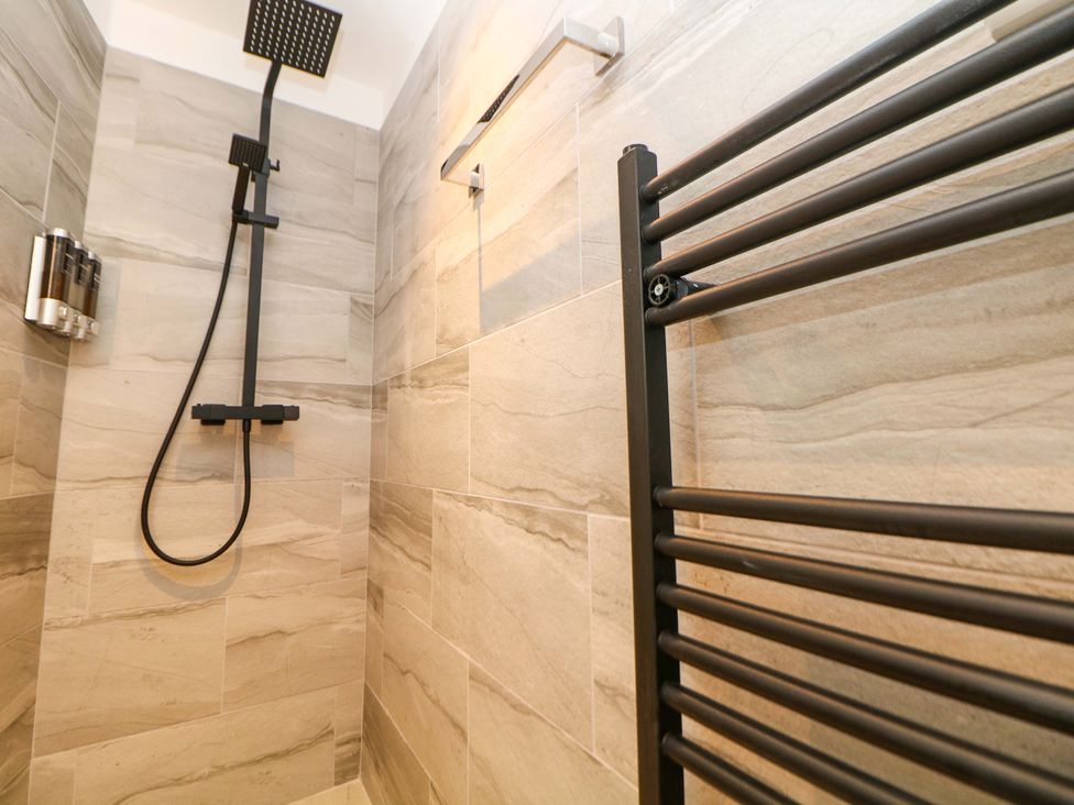 A shower with a rain showerhead and towel radiator at Dore Cabin in Sheffield