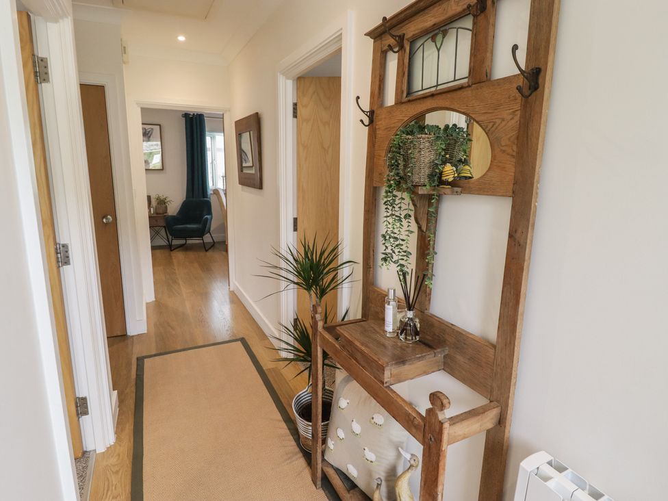 A hallway with a wooden coat rack and plant at Cornstore Cottage in Pembroke
