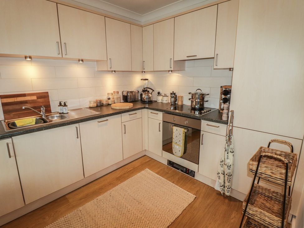 A kitchen with cabinets, sink, and stove at Cornstore Cottage in Pembroke