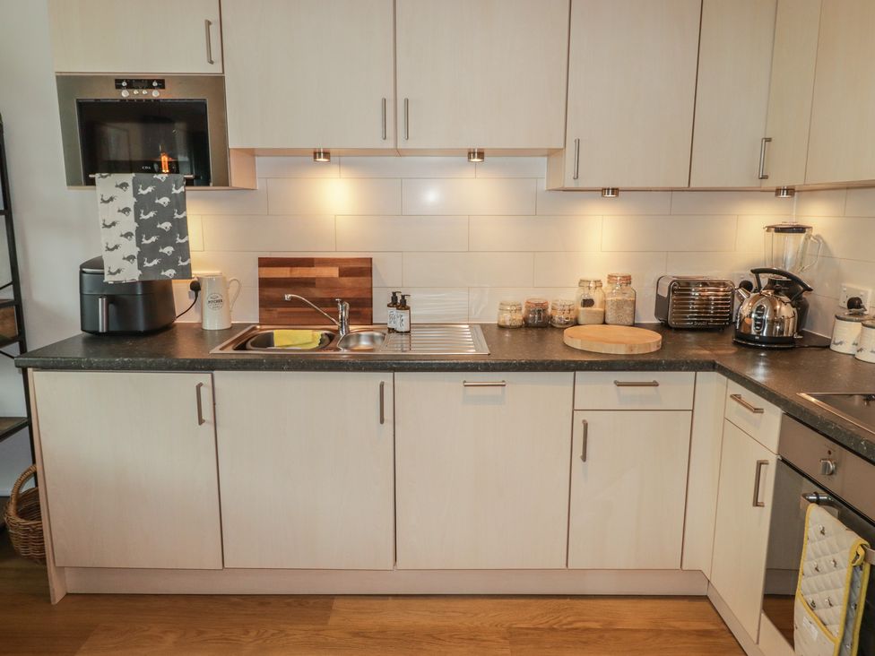 A kitchen with appliances and a sink at Cornstore Cottage, Pembroke