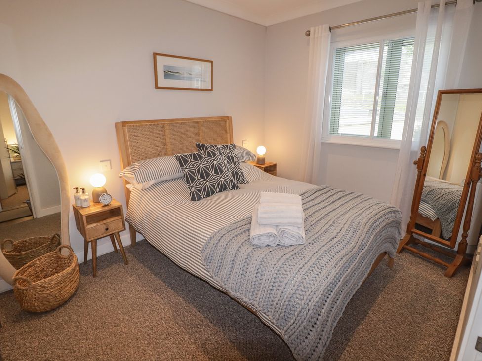 A bedroom with a bed and nightstand at Cornstore Cottage, Pembroke