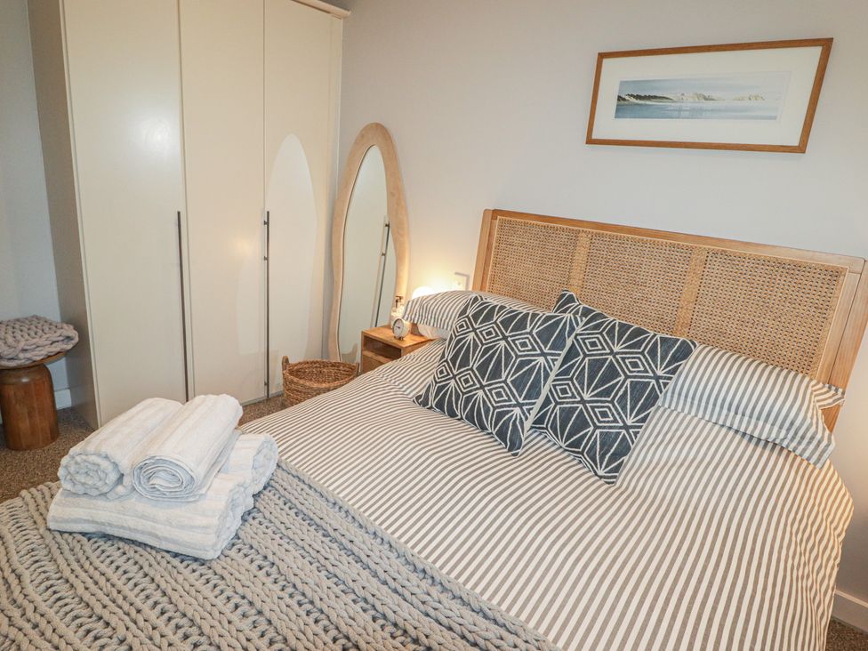 A bedroom with a bed and wardrobe at Cornstore Cottage in Pembroke