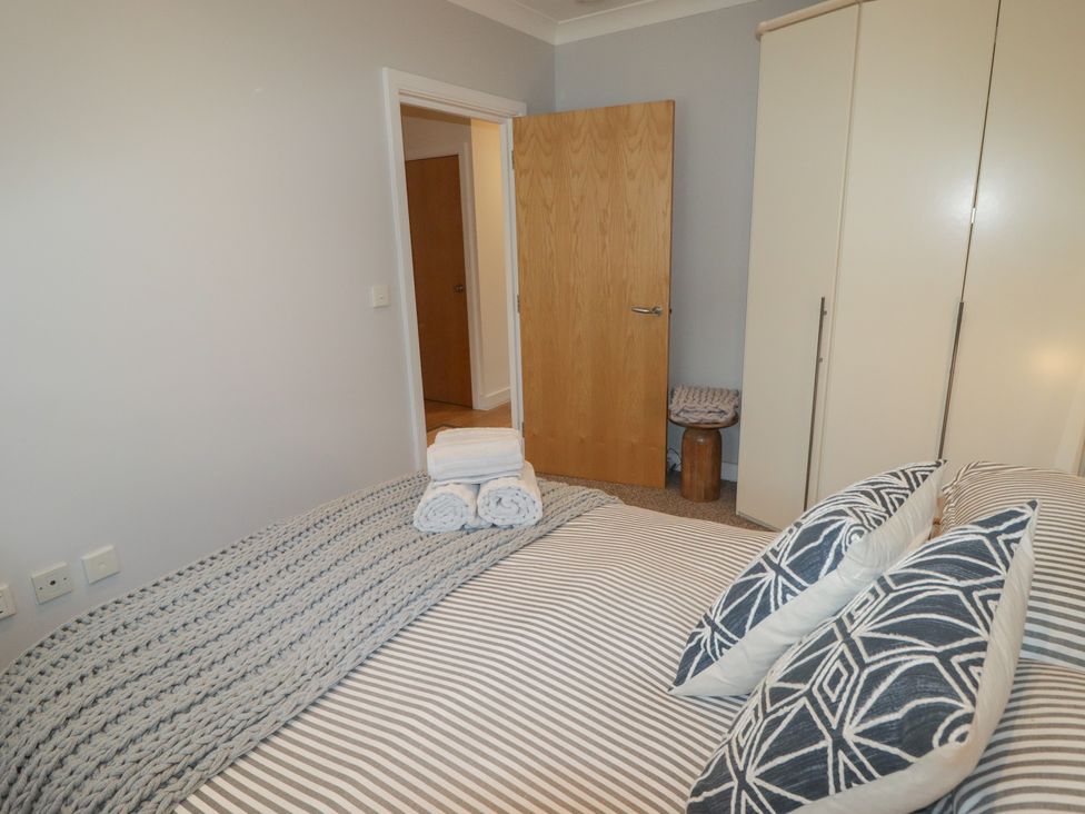 A bedroom with a bed and wardrobe at Cornstore Cottage in Pembroke