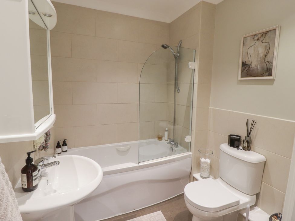 A bathroom with a bathtub, shower, sink, and toilet at Cornstore Cottage in Pembroke