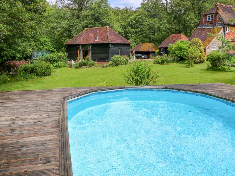 A garden with a swimming pool and buildings at Petworth Barn in Petworth
