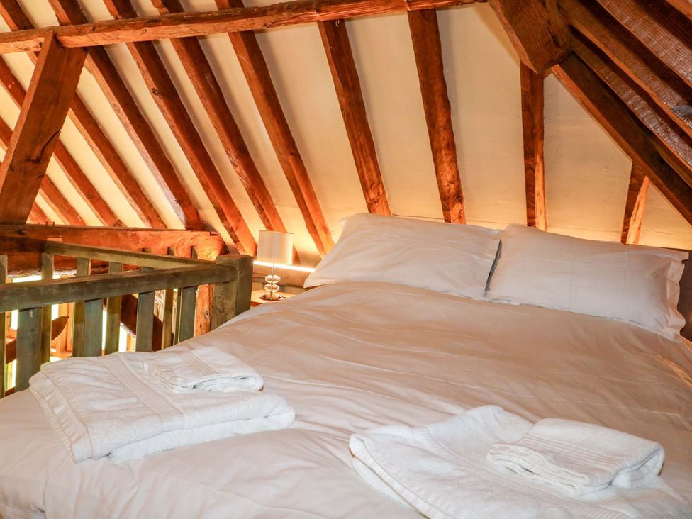 A bedroom with a bed and wooden beams at Petworth Barn in Petworth