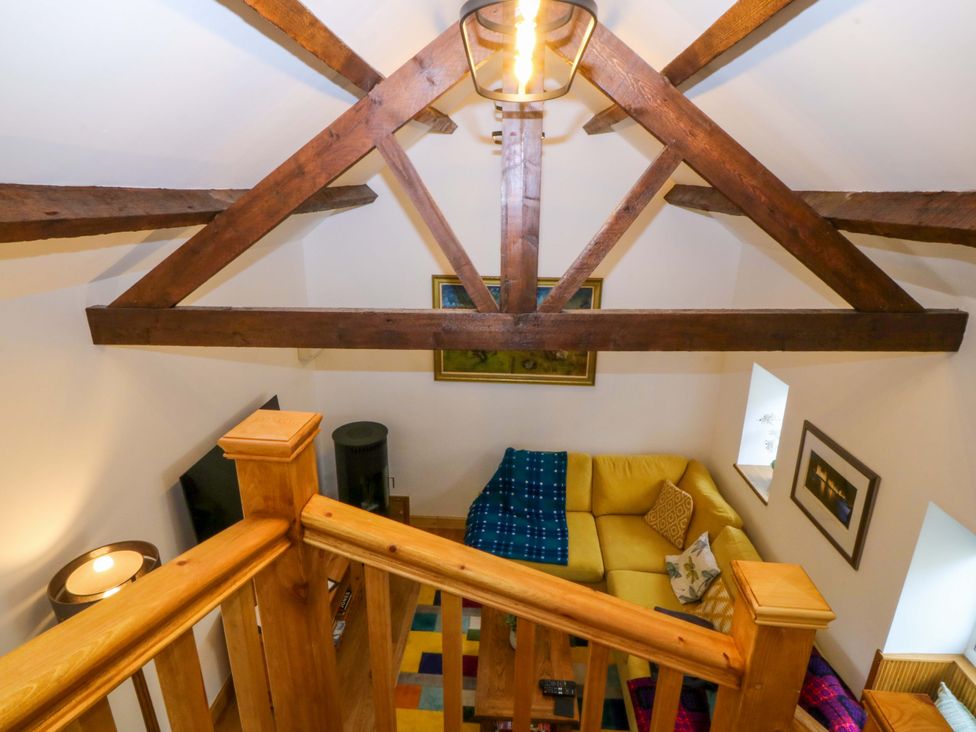 A living room with a sofa and wooden beams at Ty Loti