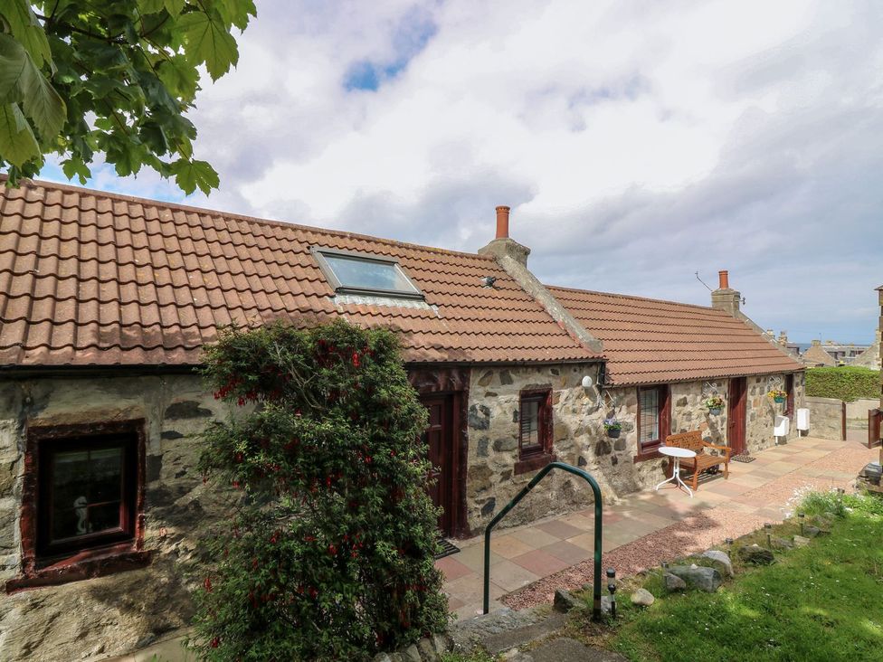 A stone house with a pathway and garden at Viola Cottage Fraserburgh