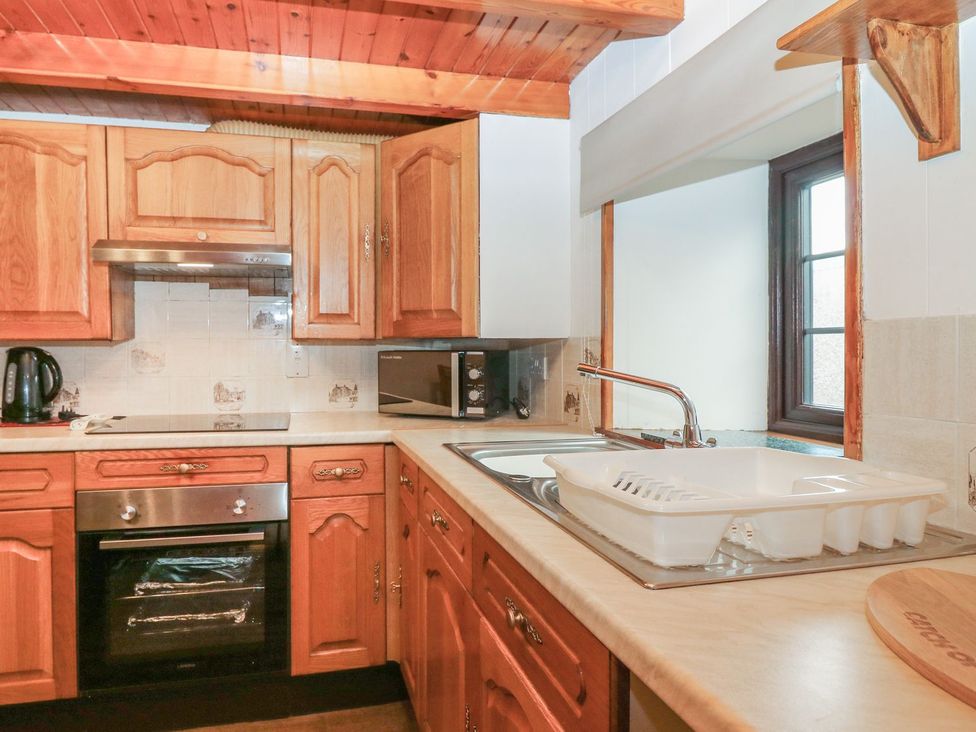 A kitchen with wooden cabinets and appliances at Viola Cottage in Fraserburgh