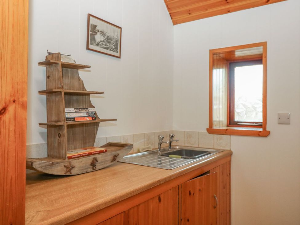 A kitchen with a sink and shelving with books at Viola Cottage Fraserburgh