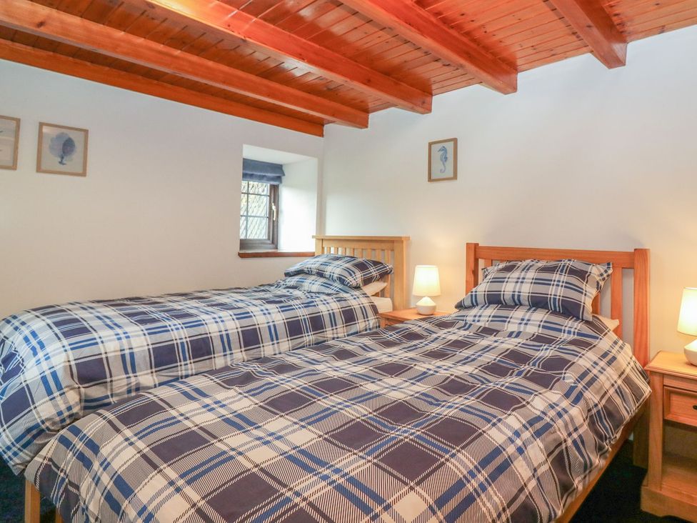 A bedroom with two beds and a window at Viola Cottage in Fraserburgh
