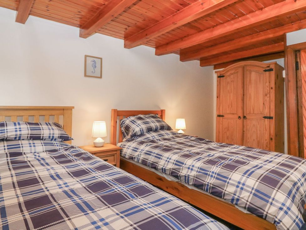 A bedroom with two beds and a wardrobe at Viola Cottage in Fraserburgh