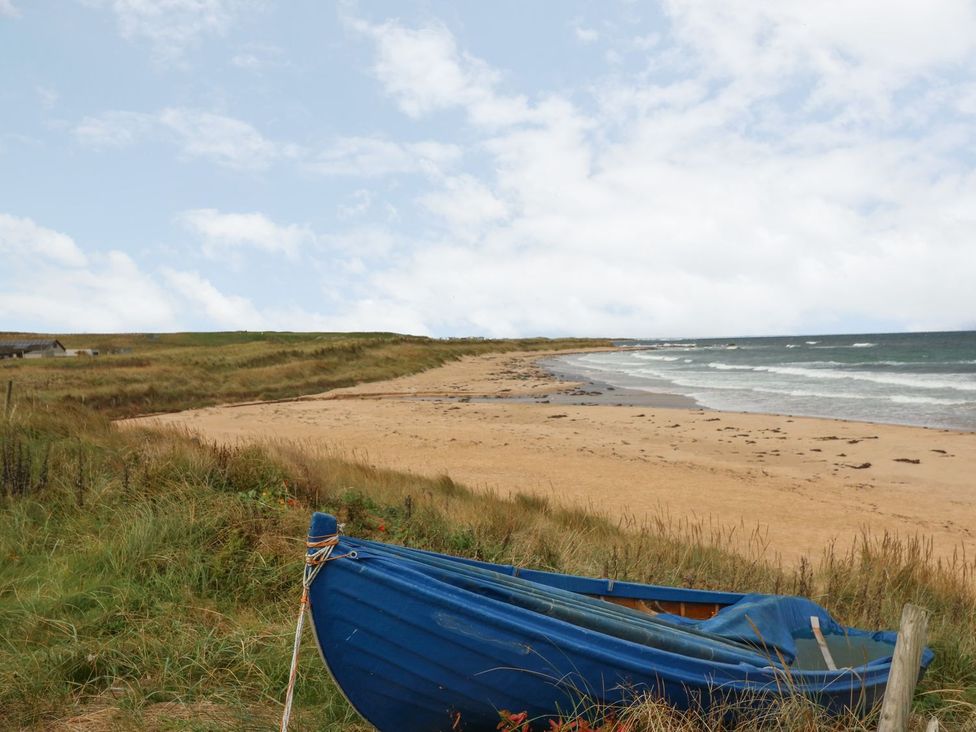 A beach with a blue boat on the sand at Viola Cottage in Fraserburgh