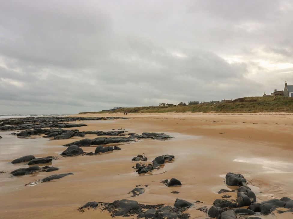 A beach with rocks and sand at Viola Cottage in Fraserburgh
