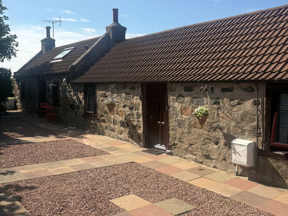 An outdoor area with a stone wall and door at Viola Cottage St Combs near Fraserburgh