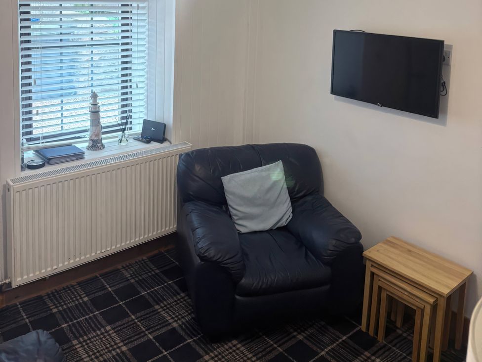 A living room with a chair and television at Viola Cottage in St Combs near Fraserburgh