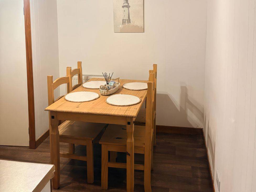 A dining room with a wooden table and chairs at Viola Cottage St Combs near Fraserburgh