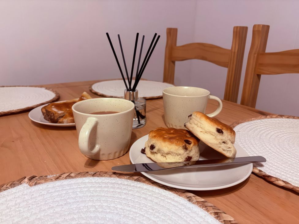 A dining room table with scones and a cup at Viola Cottage in St Combs near Fraserburgh