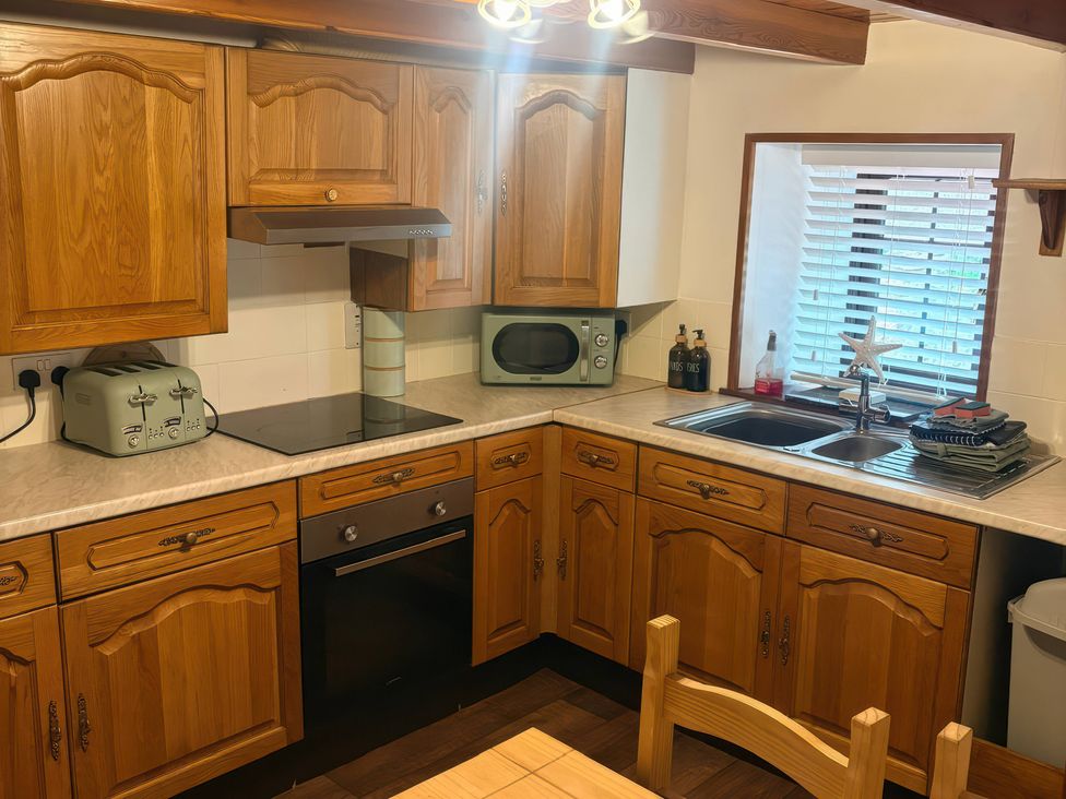 A kitchen featuring wood cabinets and appliances at Viola Cottage St Combs near Fraserburgh
