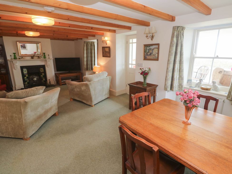 A living room with a television and table at Chyrose Farmhouse in Pendeen
