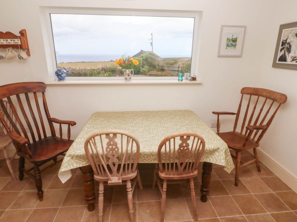 A dining room with a table and chairs at Chyrose Farmhouse in Pendeen