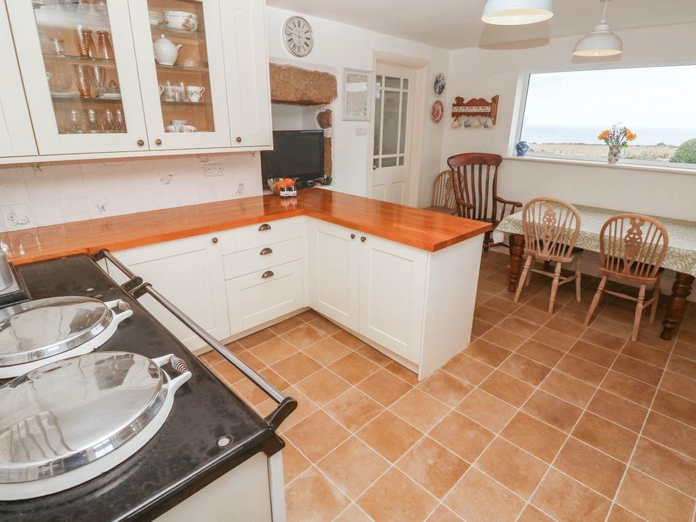 A kitchen with cabinets and a dining area at Chyrose Farmhouse in Pendeen