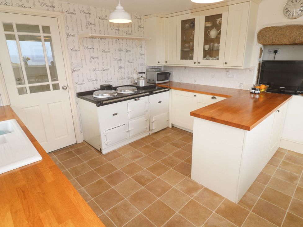 A kitchen with a stove, sink, and countertops at Chyrose Farmhouse in Pendeen