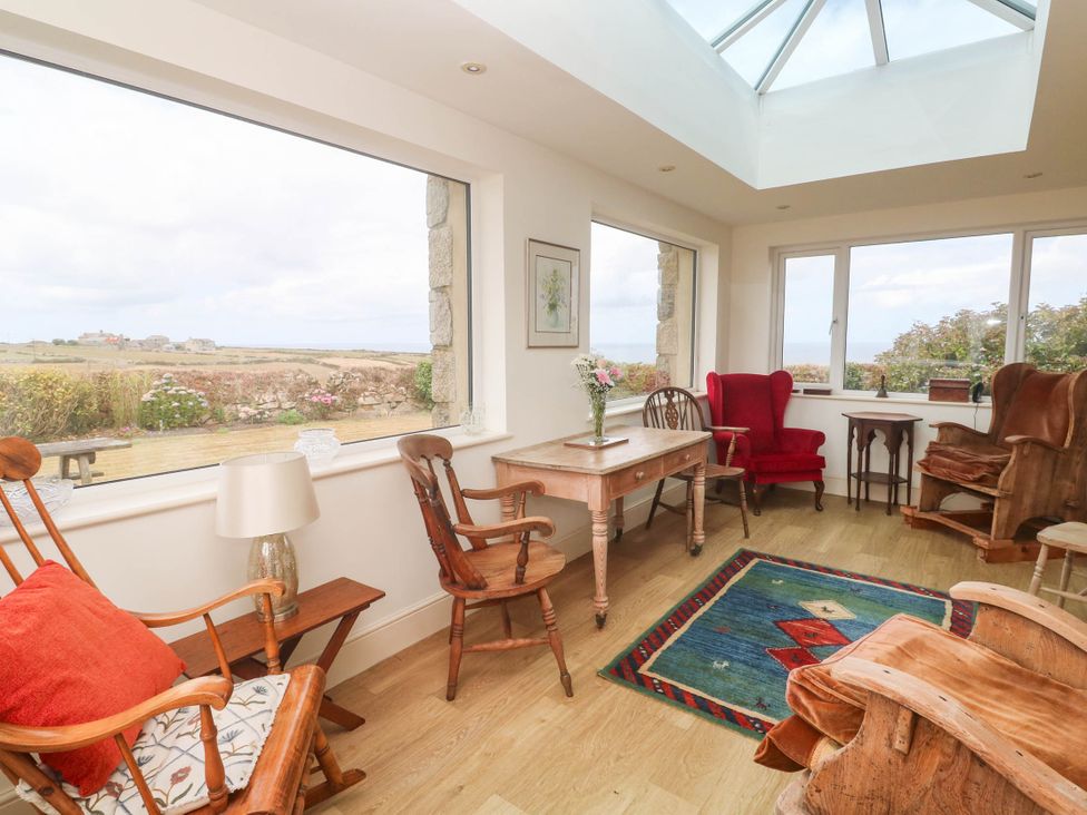 A conservatory with chairs and a table at Chyrose Farmhouse in Pendeen