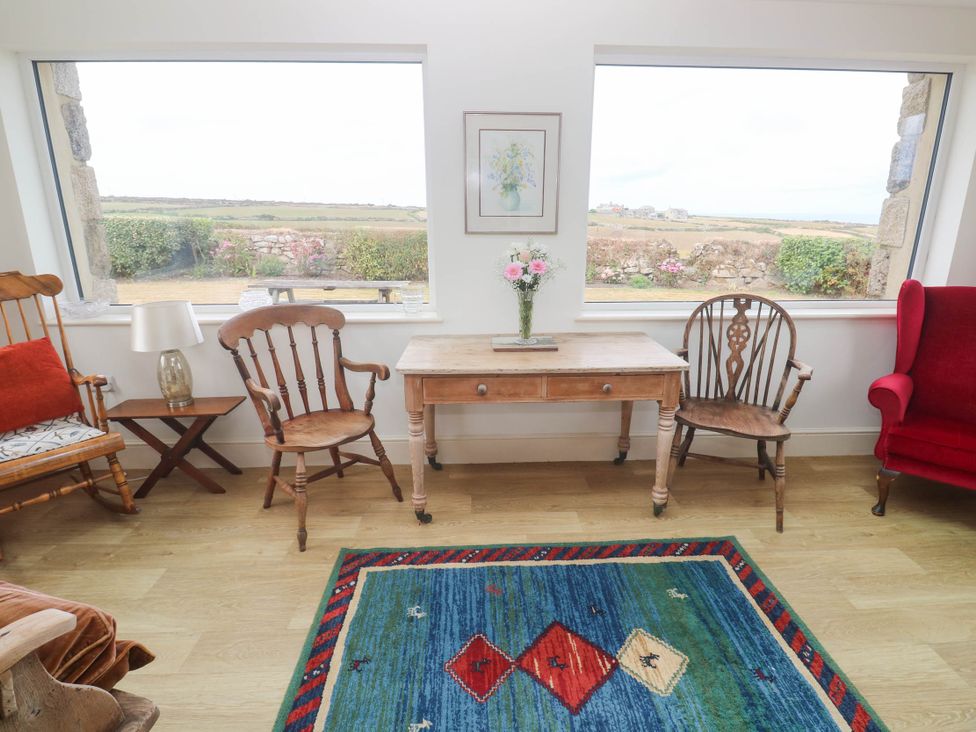 A living room with a wooden table and chairs at Chyrose Farmhouse in Pendeen