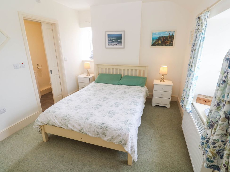 A bedroom with a bed and bedside tables at Chyrose Farmhouse in Pendeen