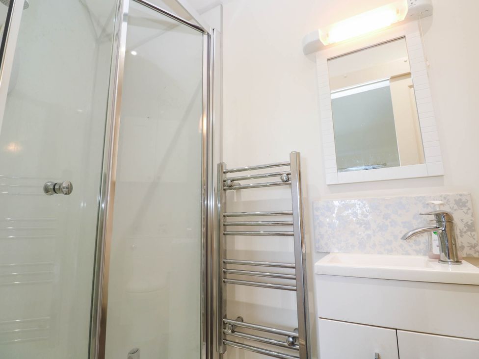 A bathroom with a shower, sink, and towel rail at Chyrose Farmhouse in Pendeen