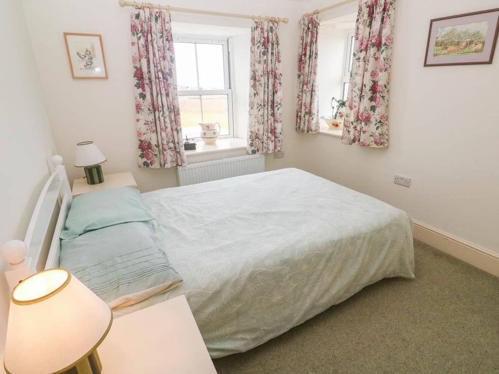 A bedroom with a bed and decorative curtains at Chyrose Farmhouse in Pendeen