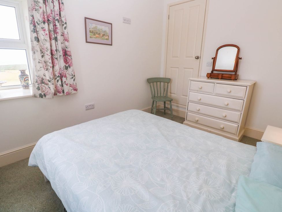 A bedroom with a bed and dresser at Chyrose Farmhouse in Pendeen