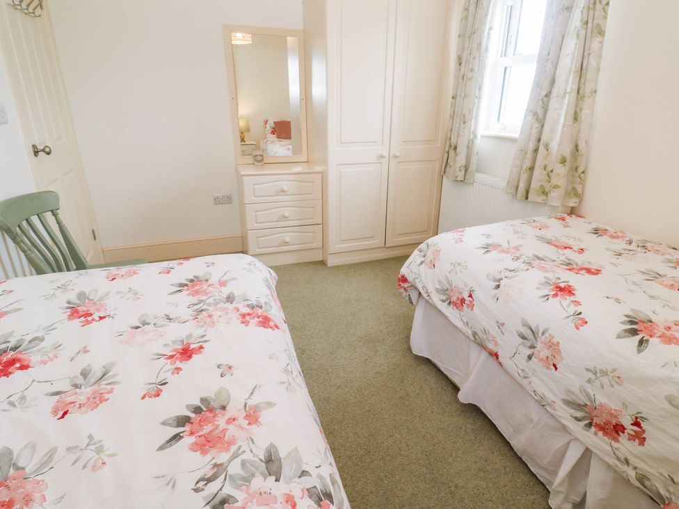 A bedroom with two beds and a wardrobe at Chyrose Farmhouse in Pendeen