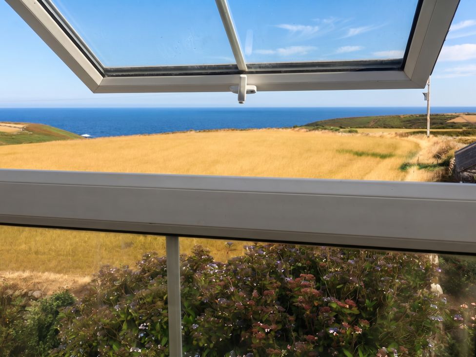 A view from a window showing a field and sea at Chyrose Farmhouse in Pendeen