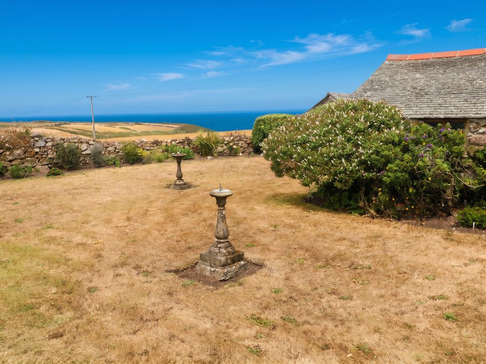 A garden with birdbaths and a stone wall at Chyrose Farmhouse in Pendeen
